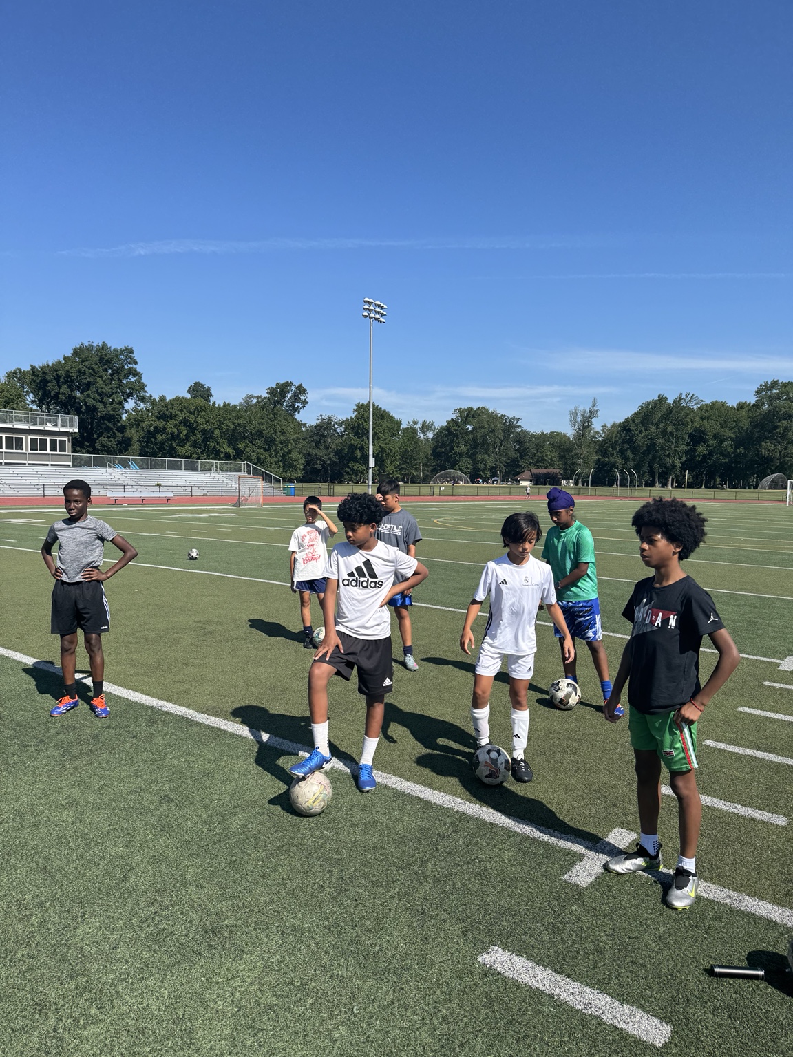 Young soccer players gathered with their soccer balls on the field during a Project Paraball group session